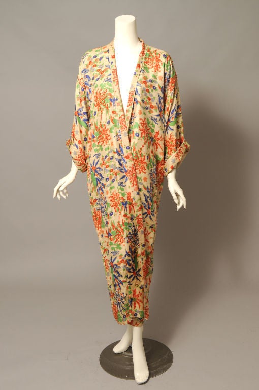 Natural colored silk pongee is printed with a colorful mix of flowers and foliage. Bright orange and blue flowers are accented by brilliant green leaves. The coat or dressing gown is lined in silk pongee, and the collar and cuffs are done in the