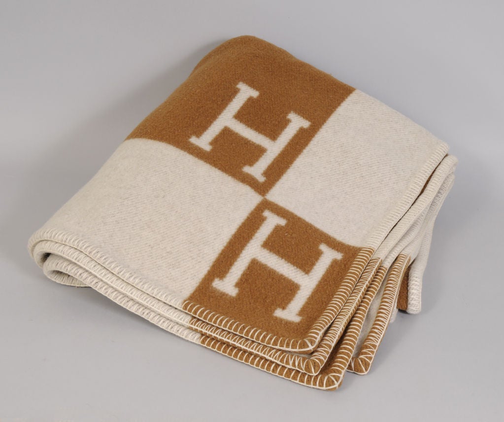 A wool & cashmere blanket in the traditional Hermes H pattern is done in camel and taupe. The color scheme revereses on the oppposite side. The balnket is in excellent condition.<br />
<br />
Measurements;<br />
70