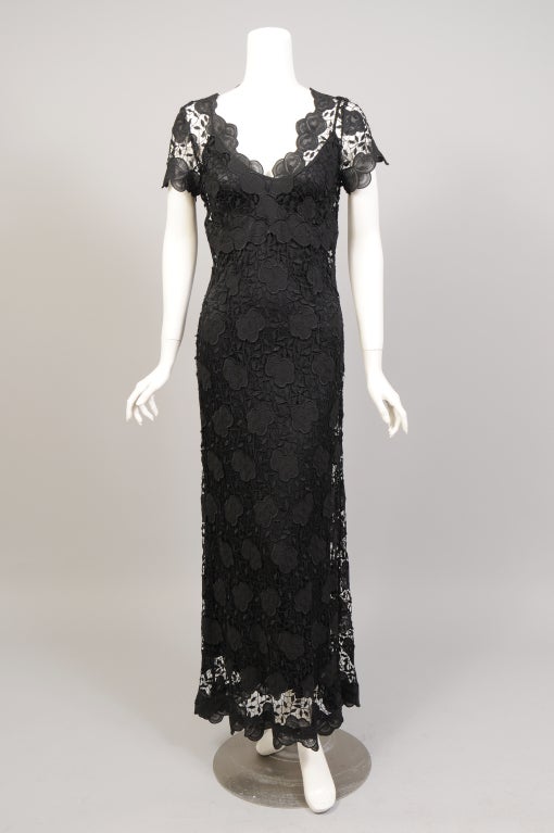 A gorgeous sheer black lace with a floral pattern is used for this sleek evening dress from Colette Dinnigan. It has a flattering V neckline, an Empire waist, short sleeves and a left side zipper. The matching slip is bias cut with a bit of stretch.