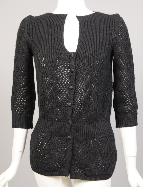 A super soft and super stylish sweater from Emanuel Ungaro is knit in an openwork pattern. The sweater has a square neckline, 3/4 sleeves, a fitted waist and black satin covered buttons at the center front. It is in excellent condition.<br />
<br