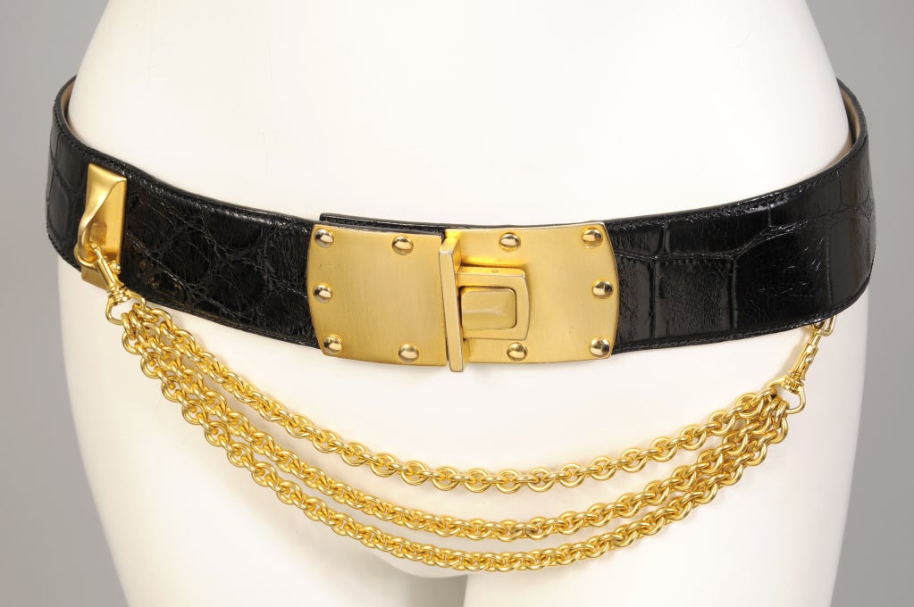 Genuine American alligator is combined with matte gold hardware and shiny gold chains in this striking black belt from Donna Karan. The chains can be unhooked adding versatility to the belt Marked a M/L it is in excellent condition.<br />
<br