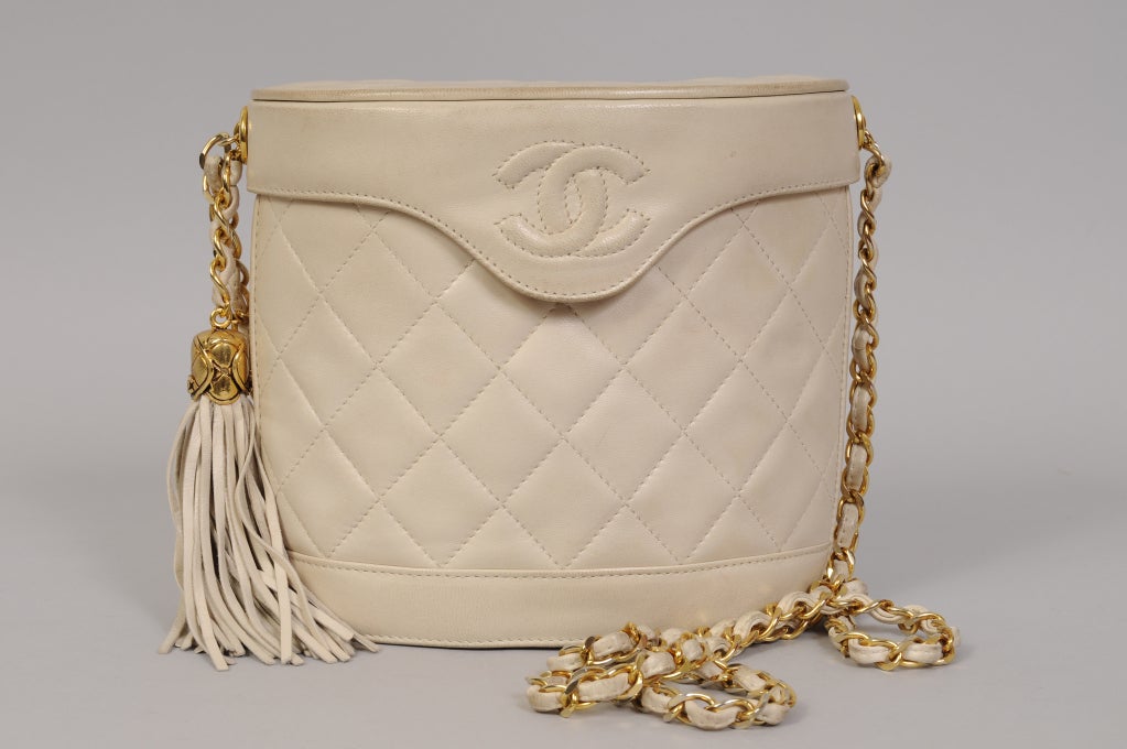 Taking the shape of a binocular case this Chanel bag has a snap closure, long leather laced chain strap with a tassel and one zippered compartment inside. It is in very good condition with minor age related darkening on the edges. It comes with the