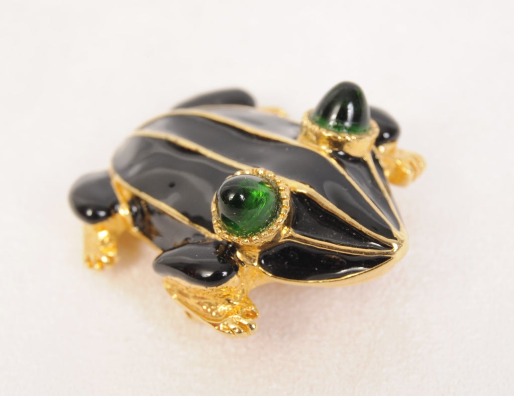A charming Kenneth Lane frog pin is done in black enamel with gold tone accents. Large green cabochon 
