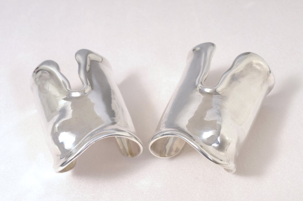 This rare pair of large sterling silver bone cuffs was designed by Elsa Peretti for Halston in the mid 1970's and retailed by Tiffany & Co. Made specifically for the right and left wrists the bump in the bracelet fits comfortably over your wrist