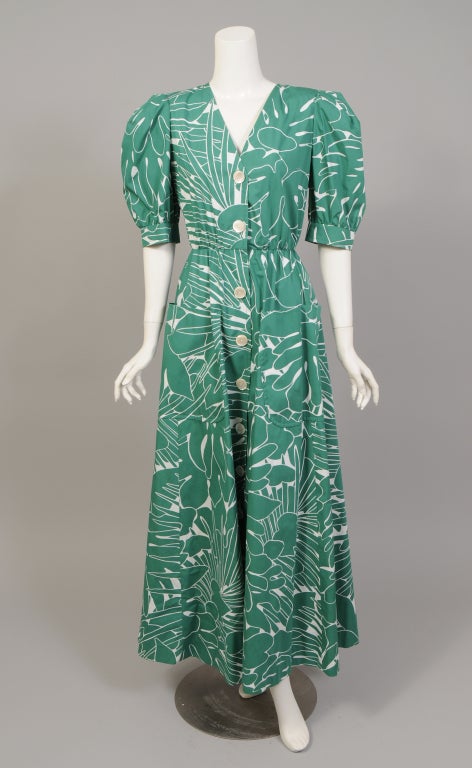 A large scale green and white leaf print creates an unmistakable summer mood in this long cotton dress from Yves Saint Laurent Rive Gauche. The shirtwaist style has a V neckline, short full sleeves, a fitted waist, two patch pockets and Mother of