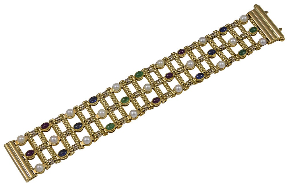 A gorgeous bracelet consisting of cabochon emeralds, rubies, sapphires and pearls, all set in 18k yellow gold .  The bracelet is 1 1/4 inches wide and 8.00 inches in length.