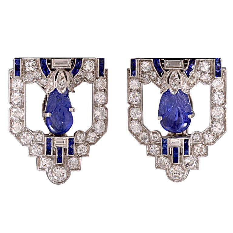 A very rare pair of Art Deco diamond and carved sapphire dress clips that can be worn as a brooch.  The diamonds are a mix of round brilliant, and baguette cuts, with a total estimated weight of 3.90cts.  The two large sapphires are a carved