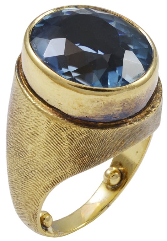 A beautifully designed, Bruno Guidi handcrafted ring. It is an oval blue topaz is estimated to be 11.30cts, and is set in an 18k yellow gold, brushed finish mounting. 

Bruno Guidi who devoted his entire career to creating magnificent,