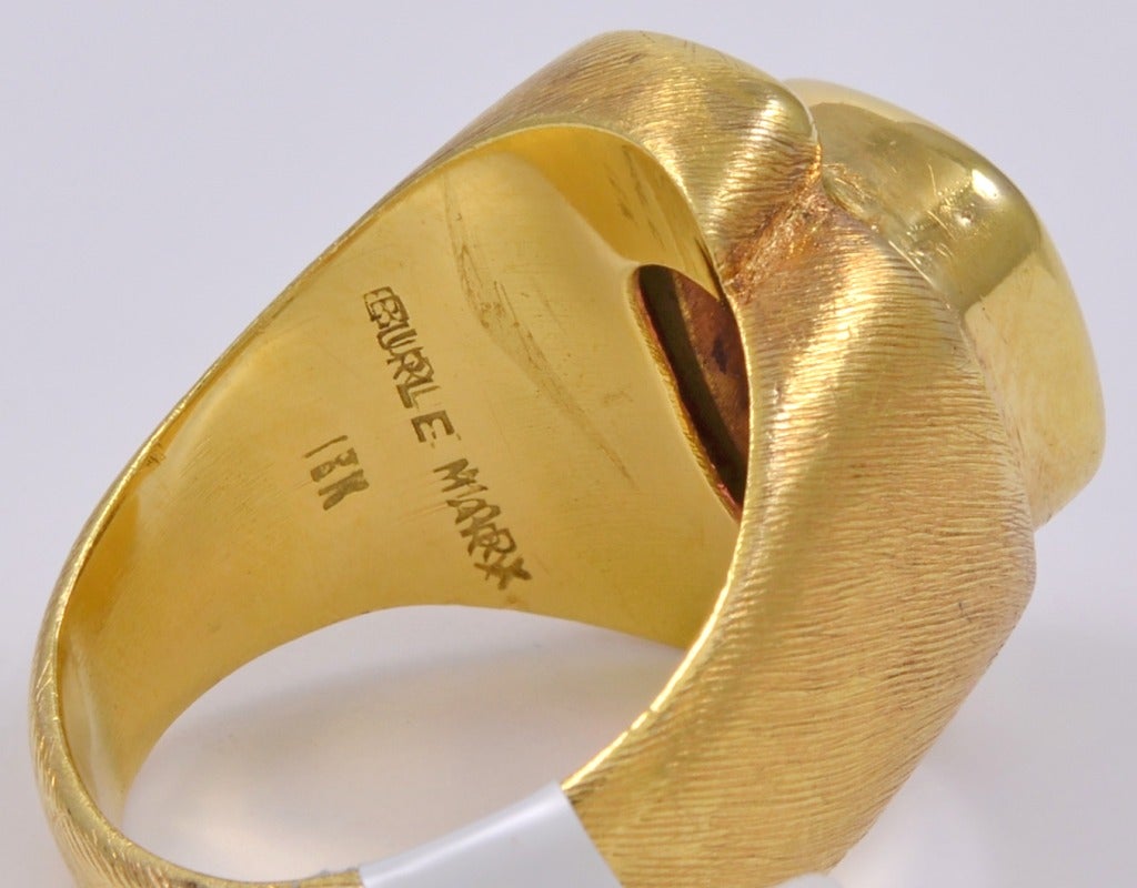 A beautiful Burle-Marx cushion shape purplish-pink tourmaline
18k yellow gold ring.  The tourmaline is bezel set, and the ring has a brushed textured finish.

Brazilian jeweler Haroldo Burle-Marx creates hand-crafted and artistic pieces adorned