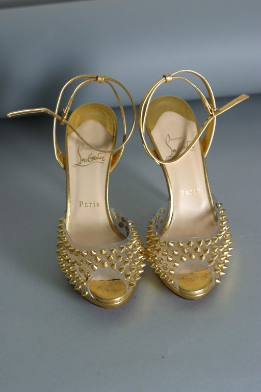 Christian LOUBOUTIN, Paris, circa 2012

Ultra glamorous pair of gold calfskin evening sandals, open toe, The clear plastic studded with gold metallic spiked studs.
Classic LOUBOUTIN red soles.
Inner sole of nude leather stamped gold

Marked