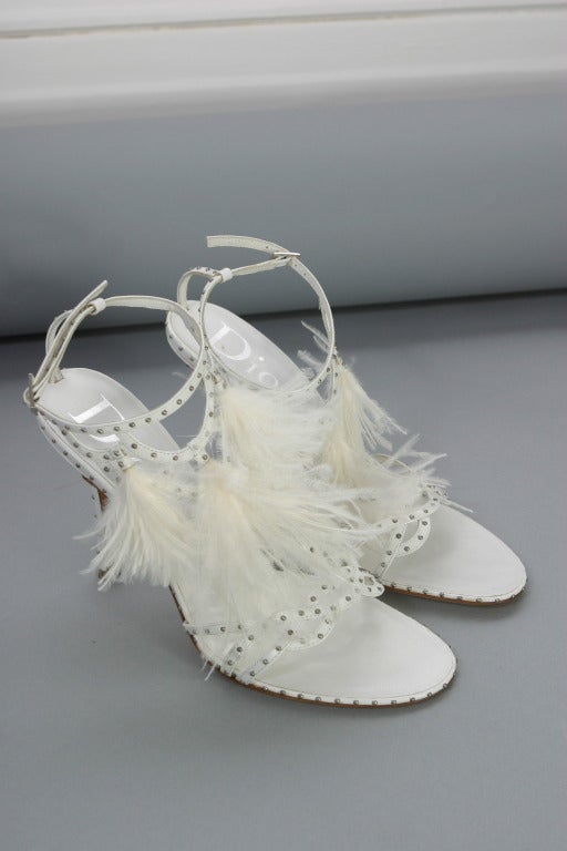Christian DIOR, by John GALLIANO,  circa 2004

Exquisite and delicate pair of white leather sandals, fully studded with tiny round  metallic domes, lined in white leather, adorned with tufts of fluffy white ostrich feathers...gorgeous!
Inner sole