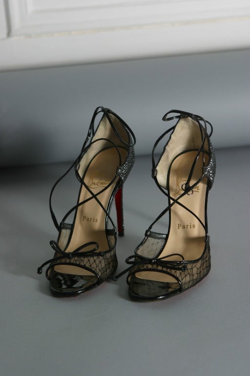 Christian LOUBOUTIN, Paris, circa 2012

Gorgeous and sexy open toe evening sandals, the back of the shoe and heel fully covered in black Swarovski crystals, the front of black geometrical  lace edged with black patent leather, bow on toes.
Inner