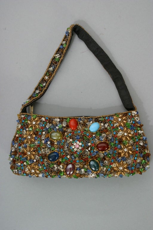 Charming, jewel like hand bag,fully embroidered  on both sides, strap as well with colored beads. lined in black, circa 1970.
The embroidery is very good, one colored stone cabochon missing on one side see picture N° 4, zip closure

DELIVERY