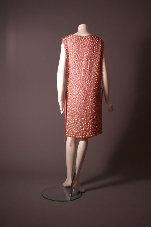 Jean Patou, by Michel Goma ( attributed ),France circa 1965- 74

A gorgeous patou couture tunic dress , formed of two fully embroidered straight flaps held by pink ties to the sides.The pink silk organza ground delicately embroidered by hand, with