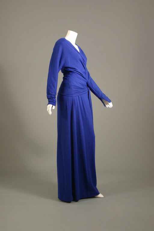 Jean Louis SCHERRER, haute couture, N° 004725, circa 1980

Long vivid blue lambswool sheath, V neck opening finishing by a cross over back fastening with bow to the front, long fluid skirt.
Zip fastening to the back . 
Zip fastening to the