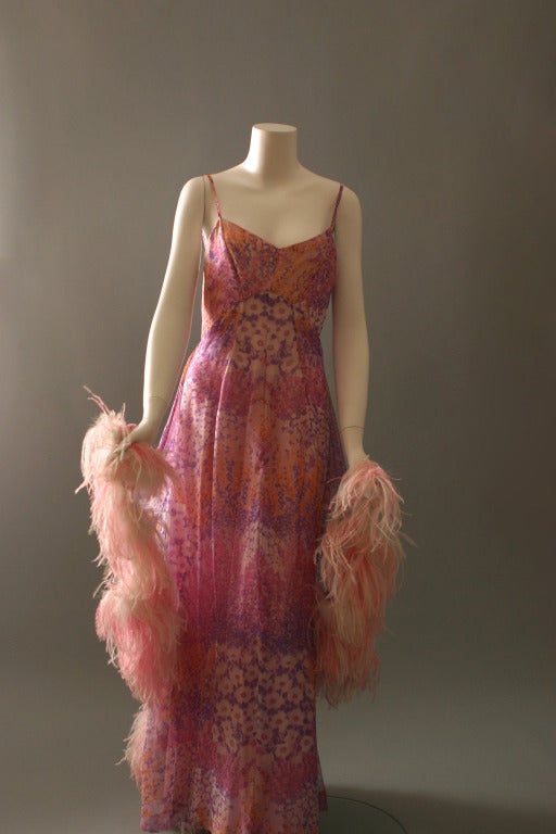 A Rosser, labelled '' ROSSER Barcelona '', colorful printed silk chiffon gown, thin straps, long flowing double skirt, trimmed with an ostrich feather, pink and white boa.
Lining in pink synthetic satin, zip closure to the back.
A lovely vaporous