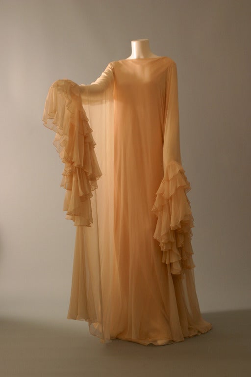 STRAVROPOULOS, New-York, Athens

A Marvelous ''Dolce Vita'', airy, evening or house dress...
the long peachy crêpe straight sheath, softened by five layers of delicately colored tea rose silk chiffon.
Ruffled sleeves for the hands, V neck