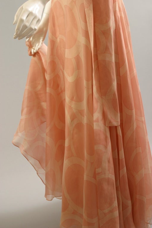 CHANEL , haute couture , circa 1970

This romantic evening gown, of a silky shimmering peach and tea rose, pop art, psychedelic print, gazar, shows a vaporous full double skirt, tying on one side by a long scarf. Sleeveless bodice, fastened to one