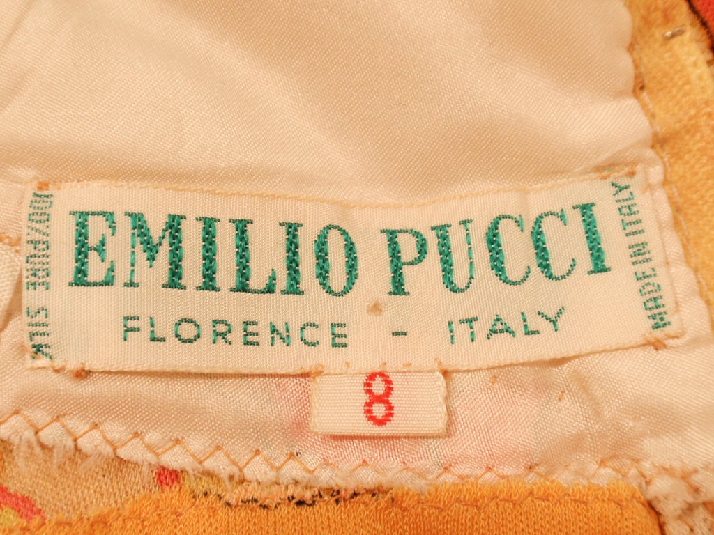 This is a fantastic vintage printed dress from Emilio Pucci. It has a pink, orange, yellow and cream bird print. It is sleeveless and zips up the back. The hem of the dress is connected with 2 slits on either side for the legs to fit through, giving