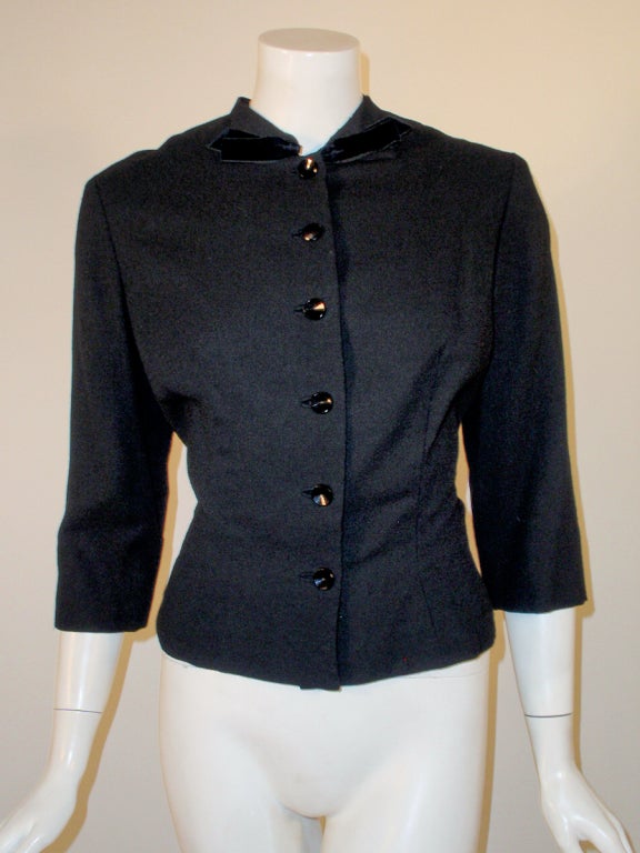 This is a charming vintage fitted jacket from designer Howard Greer. it is made of a light weight black wool, with black velvet trim on the collar and a bow at the back. Fully lined in black silk. 

Vintage Size 14, Fits like a US 6 to a small