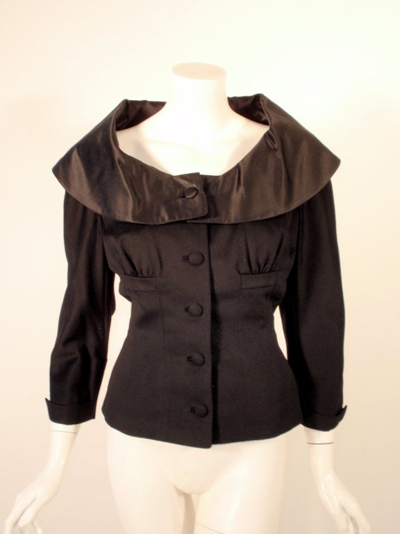 This is a vintage fitted jacket from Don Loper. It is made of a black, light-weight wool with a black satin collar and gathers at the bust. There are 5 covered buttons.

Measurements:

Bust: 36