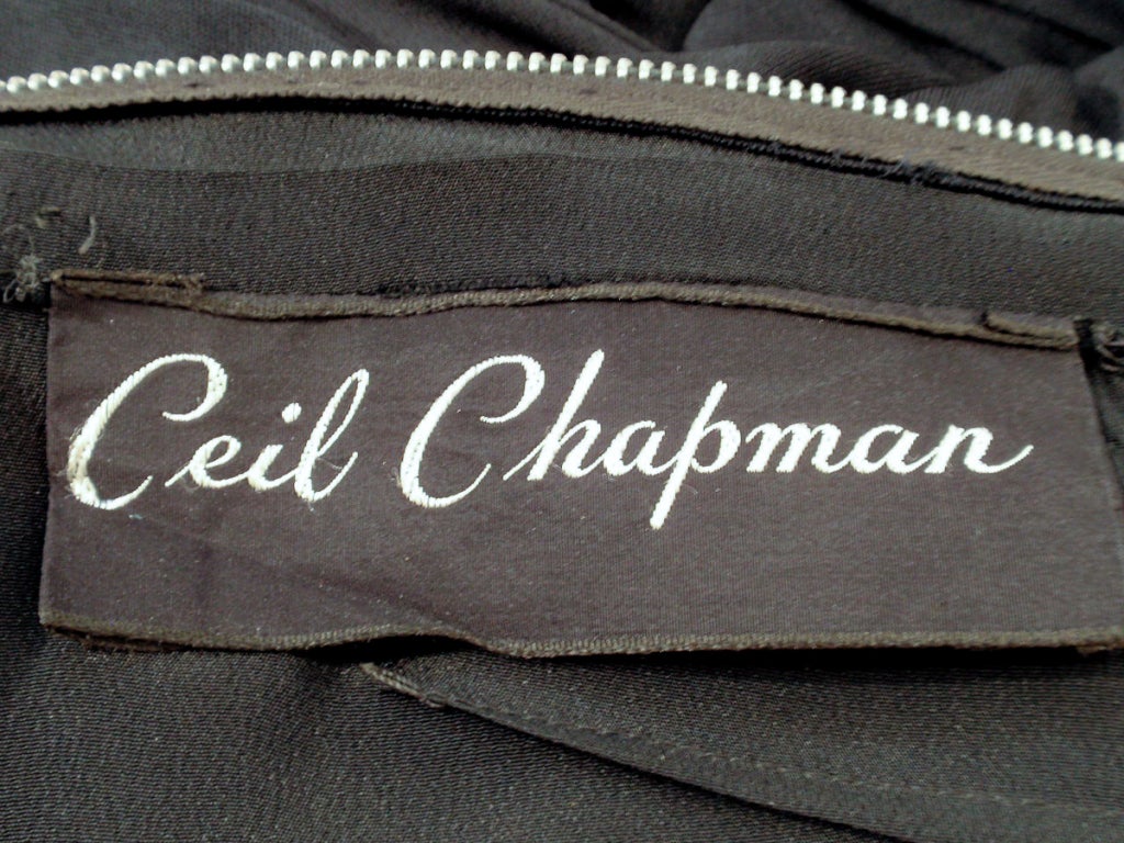 This is a highly collectible vintage piece from Ceil Chapman. It is made from a black jersey knit with a satin lining. The bodice and sleeves are ruched and the skirt is draped in the front, with side drapes, as well.

Measurements:

Bust: