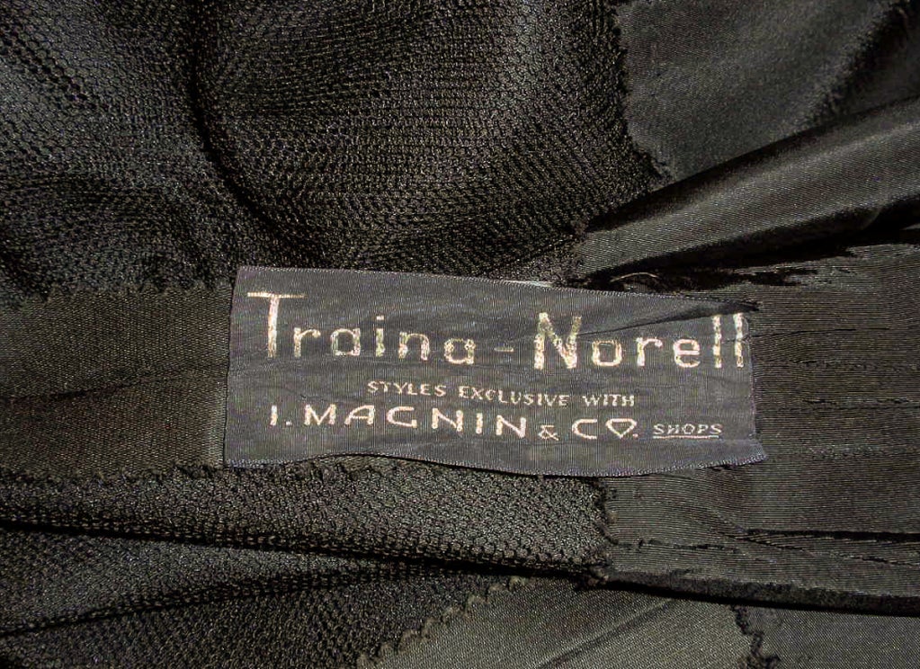 This is a wonderful vintage dress from designers Traina-Norell. It is made of a heavy black satin and has a fitted bodice, drop waist and very full skirt. There is a button front closure.

Measurements: 

Bust: 34