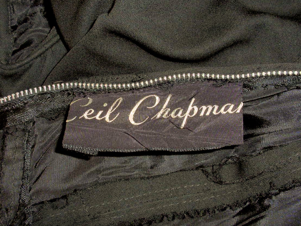 This a fabulous 1950's vintage cocktail dress from Ceil Chapman. It is made of a soft jersey knit that is draped, blouson style on the bodice and a fitted skirt. It has a scoop neckline and buttons on the sleeves. There is a metal zipper down the