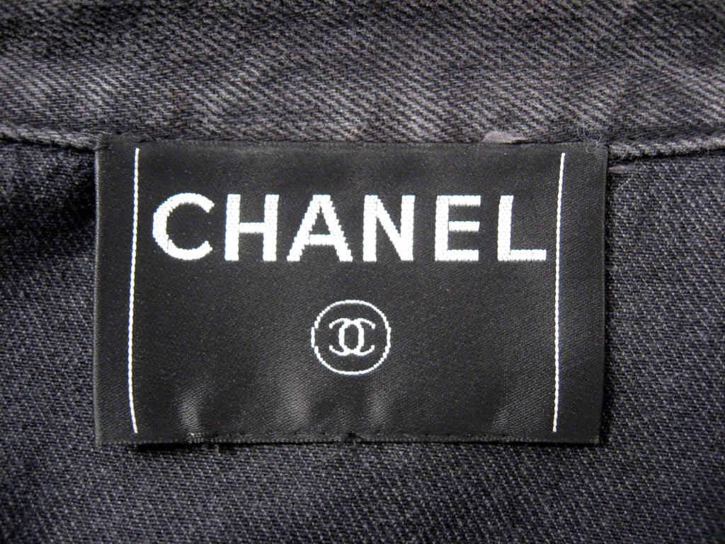 This is a stylish 2 piece pant and jacket set from Chanel. Both pieces are made of a distressed slate grey denim with copper colored metal chain woven in for embellishment. The jacket is cropped and has a metal zipper on the front and the pants have