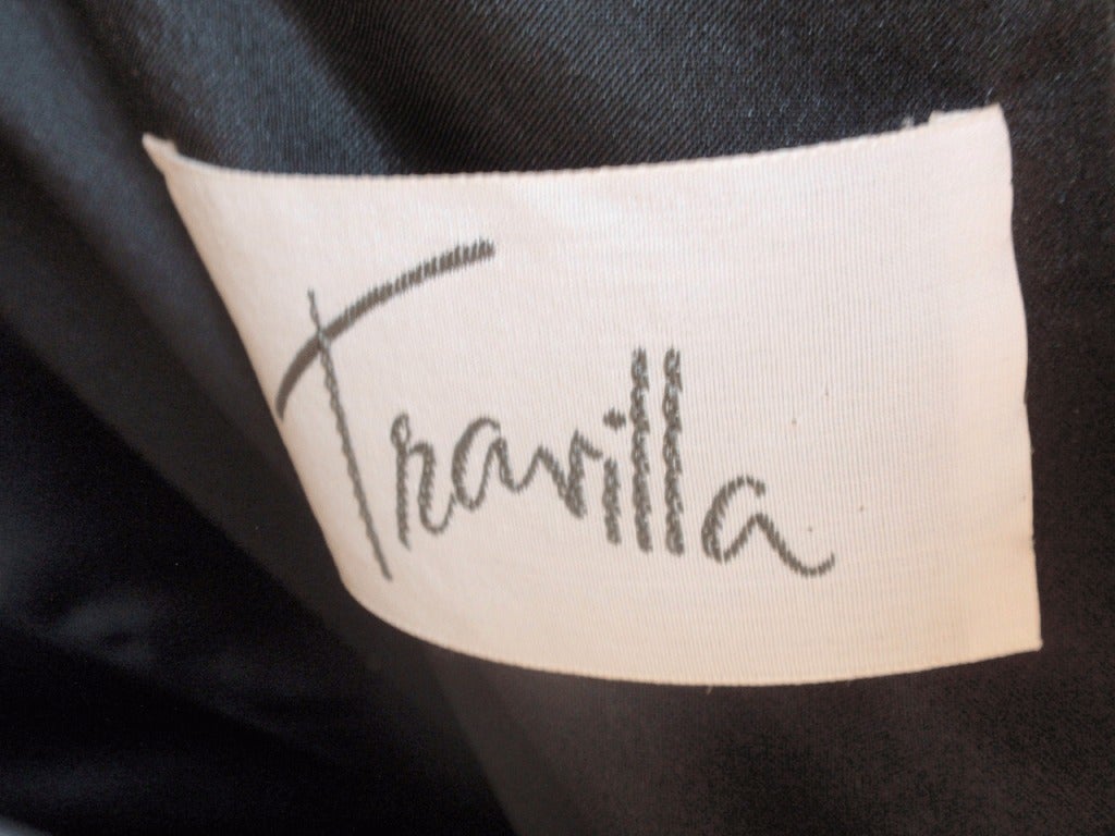 This is a lovely black cocktail dress with long sleeves by Travilla from the 1980's.
The Dress has a zipper in the back, floral detail on the front and on the bottom of the Sleeves.  The Sleeves are sheer as well as the shoulders and back line.  