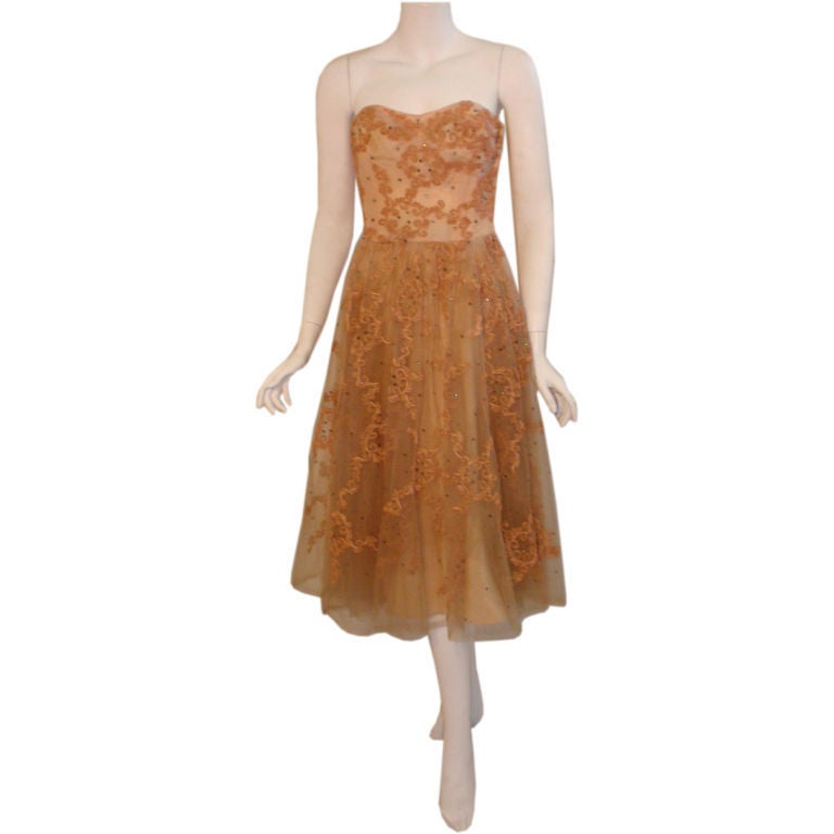 This is a vintage light pink rose strapless cocktail dress by Ceil Chapman from the 1960's. The dress has an overlay of tulle with silk embroidery and rhinestones. The tulle skirt is gathered at the waist and has an underlayer of crepe. It zips up