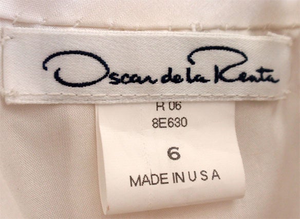 This is white and black long strapless gown by Oscar de la Renta. It has a structured bodice, full skirt, and a black and white satin bow. Measures:<br />
Size 6<br />
Length: 58