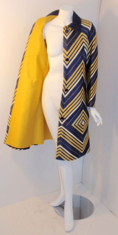This is a blue, yellow, and white striped geometric print coat by Travilla, from the 1970's. The coat has four blue buttons down the front, a yellow lining, a blue collar, and two diamond shaped open pockets on the front.<br />
<br />
Measures:<br