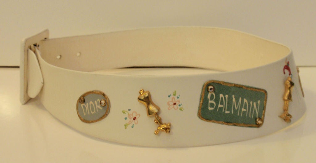 This is an adorable novelty belt that was made for Saks Fifth Avenue by Calderon. It is made of white leather and has designer names painted on it and metal dress form  and rhinestone embellishments.

Measurements:

Length: 27