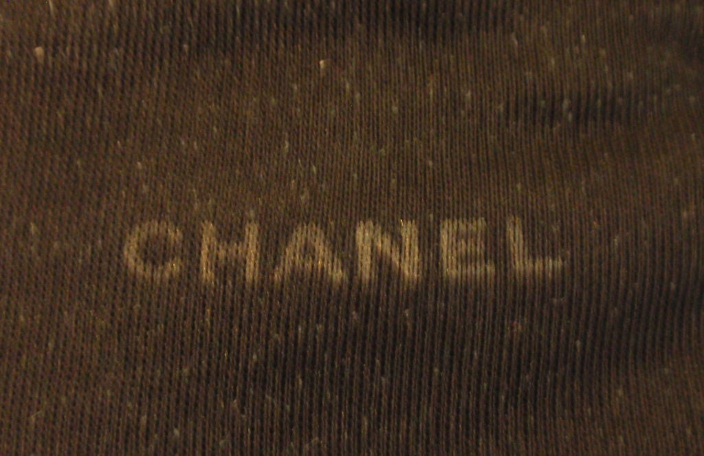 This is a pair of black quilted suede elbow length gloves by Chanel, from the 1990's. They have gold zippers, a hidden interior pocket, adjustable snaps to fit the wrist, a black silk lining, and gold Chanel logo details. The gloves are a size 7