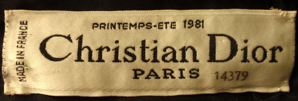 This is a long black gown with cream colored puffed sleeves by Christian Dior Haute Couture, from 1981. The gown has a slit up the side, a square neckline, zipper up the back, and constructed bodice with boning, and a black silk lining.<br />
Size