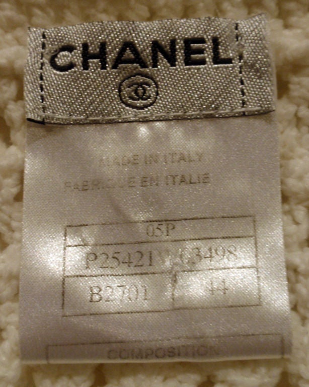 This is a white sweater jacket by Chanel, from the 1990's. The jacket has black logo buttons up the front and black silk detail at the neckline, cuff, and hem. <br />
Size #44<br />
Measures:<br />
Length (Shoulder to hem): 21 1/2