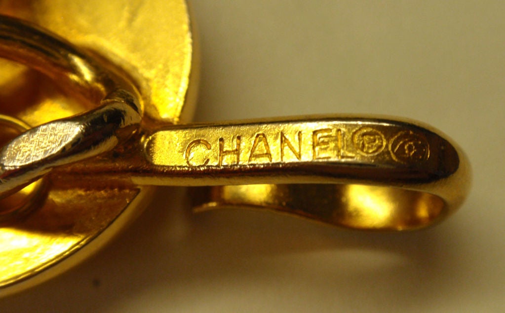 This is a gold chain link logo belt by Chanel, from 1984. The belt has three strands in the front, one strand in the back, two gold logo 