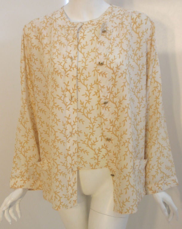 This is a two piece cream and yellow print silk blouse and tank set by Chanel, from the 1990's. The blouse has five gold logo buttons down the front and two open patch pockets. The tank has a scoop neckline with top stitching