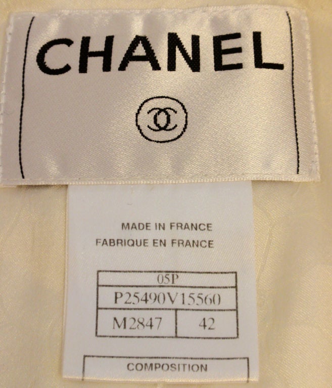 This is a white jacket with faux pearl logo buttons and sequins all over by Chanel, from the 1990's. The jacket has two small pockets in the front, bell cuffs, and a cream floral logo print lining.<br />
<br />
Measurements:<br />
Size #42<br