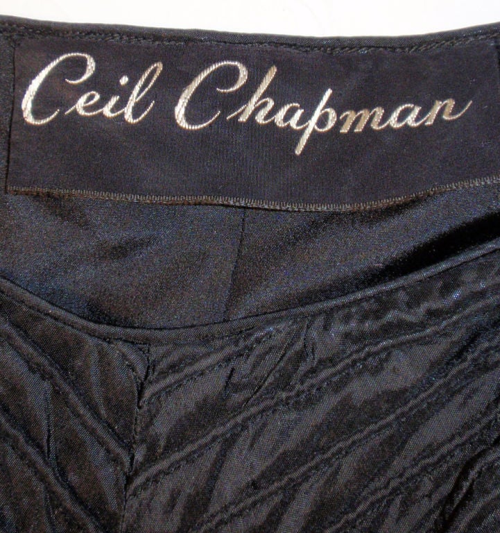 C'est une jolie robe de cocktail vintage des années 50 de la créatrice Ceil Chapman. Il est fabriqué à partir d'un taffetas noir épais qui a été épinglé pour créer un motif en chevron donnant une texture unique au tissu. Il présente un corsage