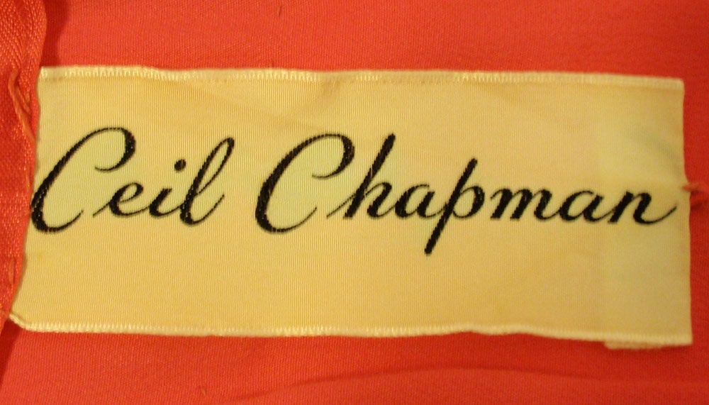 This is a charming and collectible vintage cocktail dress from Ceil Chapman. It is made of a darker pink chiffon with a pink silk lining and a zipper up the back. The chiffon is gathered at the waistline and the bust, as well as on the cap sleeves.