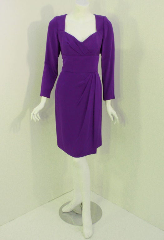 This is a sophisticated indigo purple cocktail dress from Travilla, with drape pleating at the waist and bust. It has many fine sewing details such as a hand sewn zipper in the back of the dress and snaps at the cuffs. The dress is lined with a