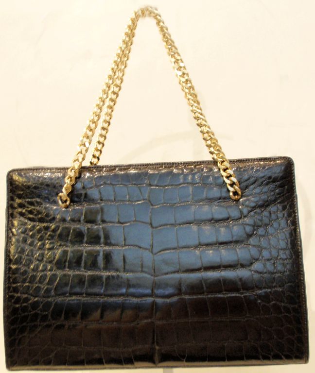 This is a lovely vintage handbag from the 1950's. It is made out black alligator skin with a black leather interior. There are 2 gold chains for a handle, and a gold clap on the top. Inside the bag there are 2 side pockets and a zipper pocket. Made