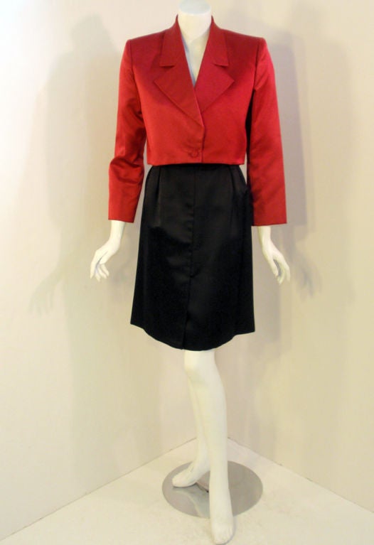 This is a charming 2 piece skirt and jacket ensemble from Andre' Laug. The cropped jacket is made of red sating, lined in black. The skirt is an a-line with 2 front pleats. Made in Italy.

Measurements:

Jacket:

Length: 17