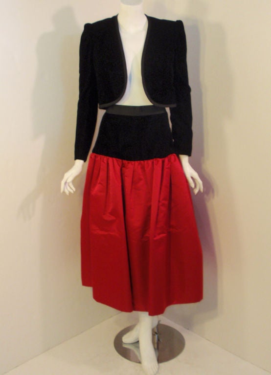 This is a formal 2 piece skirt and jacket set from Adolfo.

The cropped bolero style jacket is made of a black velvet with black lining, and the skirt is made of a heavy red satin with black velvet at the fitted waist/hips. This was sold at Saks