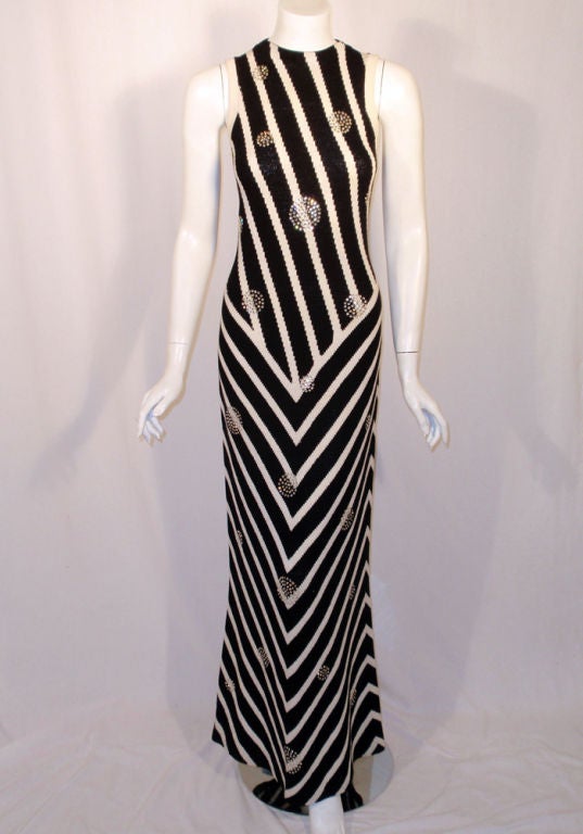 This is a swanky form fitting vintage evening gown from Adolfo. It is made from a silk/cotton blend knit, black and white striped, with various size rhinestone circles scattered about the pattern. There is a zipper up the back and teh dress is