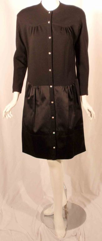 This is a black cocktail dress with a wool knit bodice and satin skirt by Geoffrey Beene, from the 1980's. The dress has crystal buttons all down the front.

Length: 39