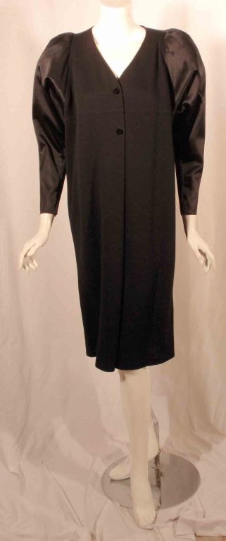 This is a black knit cocktail dress with puffy long satin sleeves by Geoffrey Beene, from the 1980's. The dress has a v-neckline with two black jewel buttons and tulle in the shoulder.

Measurements are provided for best fit, please review them