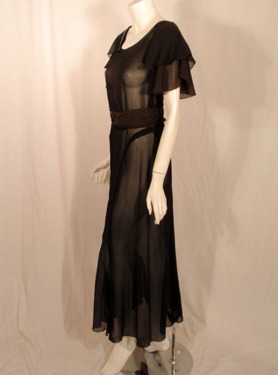 This is a fantastic Vintage, and highly collectible, evening dress from the 1920's. It is made of a black sheer chiffon and has beautiful beading and rhinestone work on the right shoulder and side. The dress is cut on the bias, so there is a lovely